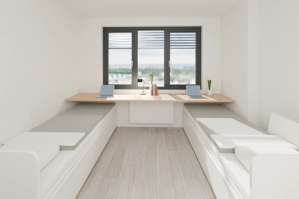 Twin studio Type 01 – view from the kitchenette to the window: two daybeds with storage drawers along the side walls and an oak desk running wall to wall under the window